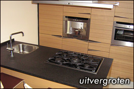 Het aanrecht van deze Italiaanse design keuken is in gebrand graniet uitgevoerd.