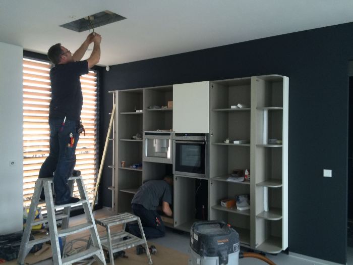 Joop is bezig met de montage van de plafond afzuigkap van deze Snaidero keuken.